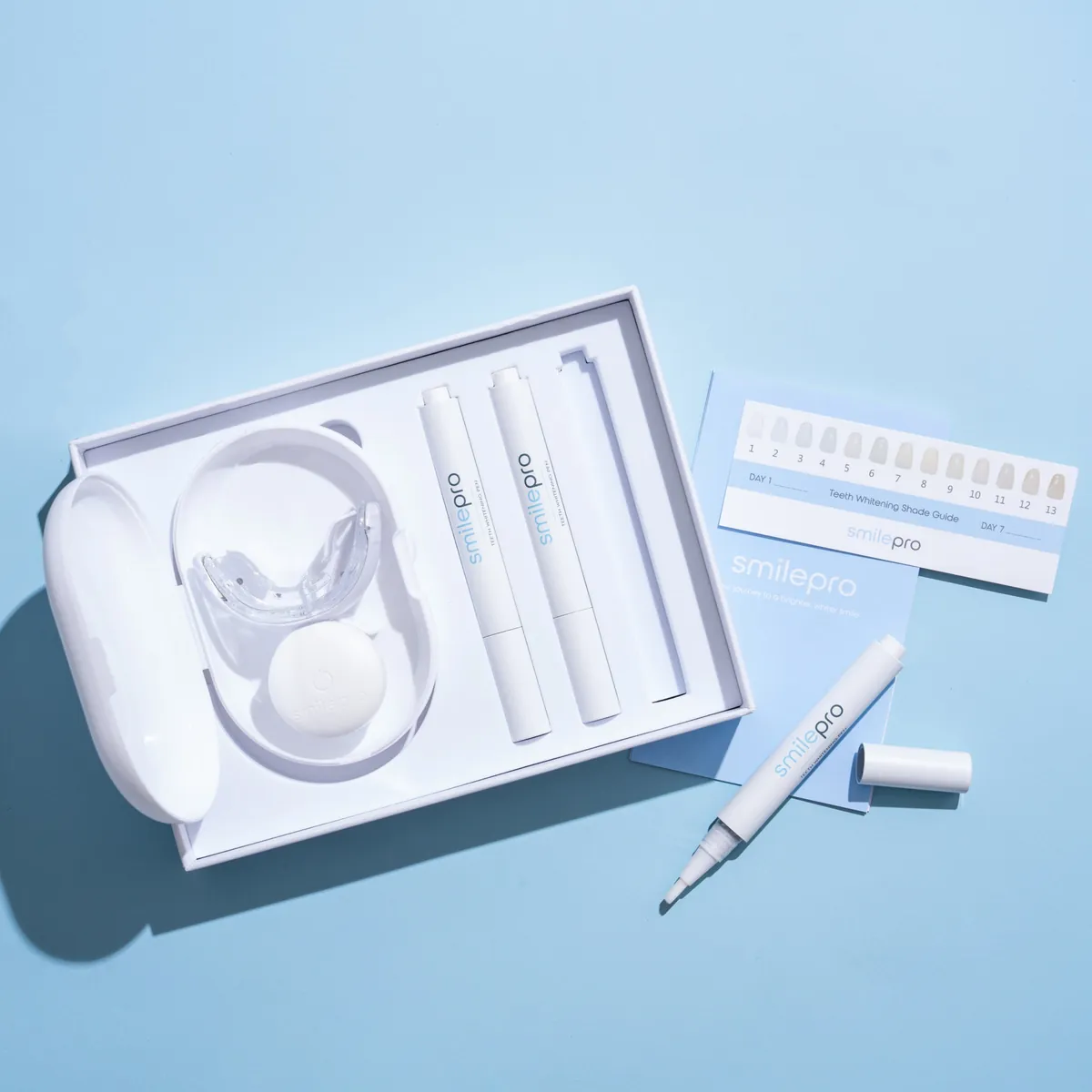 SmilePro kit open: LED mouthpiece in its charging case, gel pens, shade guide and instructions